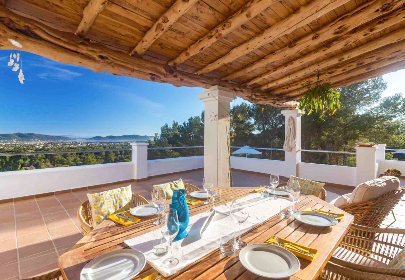 La terrasse de la Villa Casiopea avec tables et chaises et deck, donnant sur la mer.