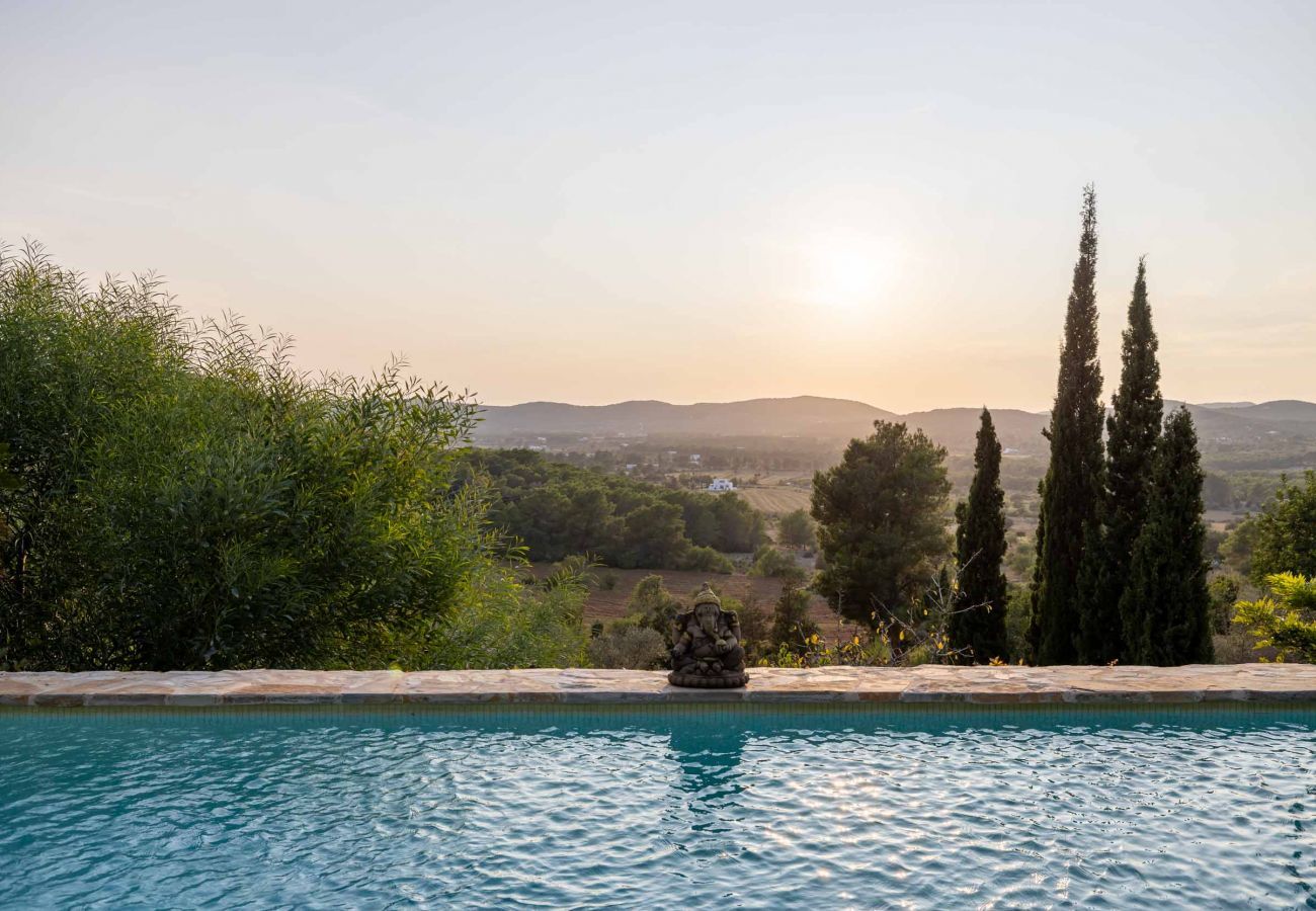 Coucher de soleil depuis la piscine privée avec le cadre naturel d'Ibiza en arrière-plan